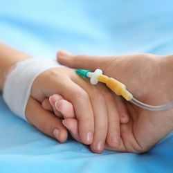 parent holding a child's hand in hospital