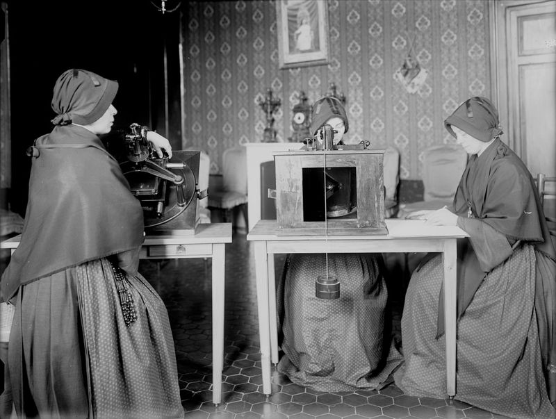 Three nuns sitting a table with photographic plates in front of them. The picture is in black and white