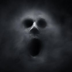 A ghostly faces presses out of the dark. The face's eyes and mouth are just black holes in an otherwise pale grey face.