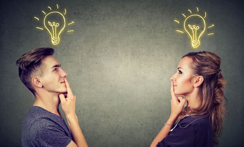 A man and a woman look at each other while lightbulbs appear above their heads to show they are thinking. 