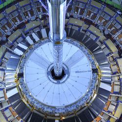 Photograph of the Large Hadron Collider, blue-tinged concentric rings of metallic sheets with a metal pole in the middle