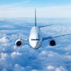 Passenger civil airplane jet flying at flight level high in the sky above the clouds and blue sky. View directly in front