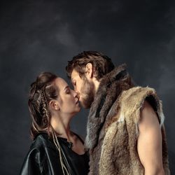 Post-apocalyptic couple kissing, dressed in fur, on a black background