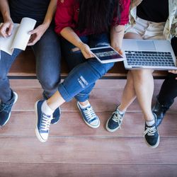 view from above of young people sat on a bench, some holding laptops and notebooks