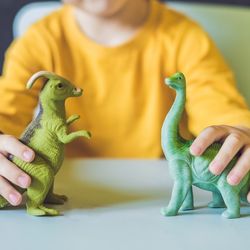 Young boy playing with dinosars doing the voice parts for both 