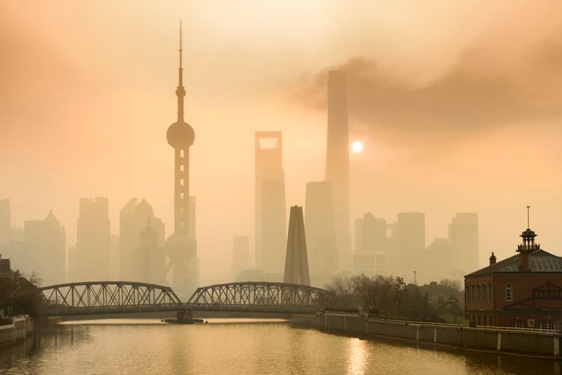 View of Shanghai skyline with orange sky; the skyscrapers are partially obscured from view due to the haze in the air from the pollution