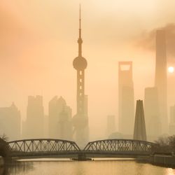 View of Shanghai skyline with orange sky; the skyscrapers are partially obscured from view due to the haze in the air from the pollution