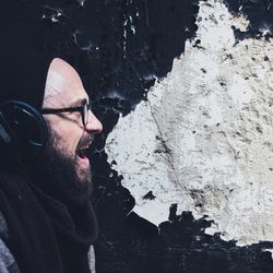 A man shouting and talking against the backdrop of a black old wall.