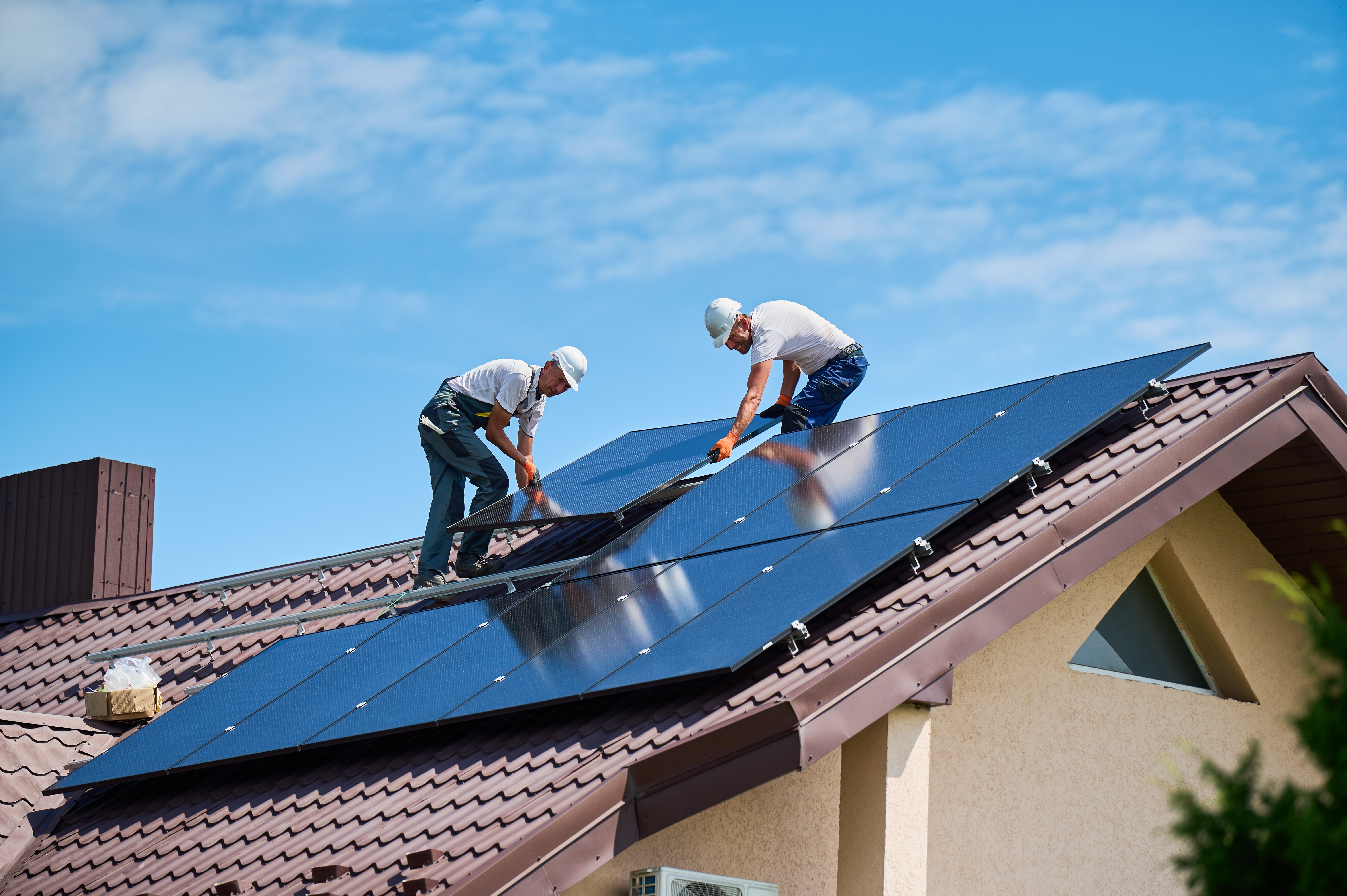 Two Workers building solar panel system on rooftop of house