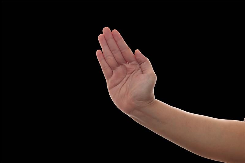 A photo of a hand preparing to make the slap action. The hand is set against a black background.