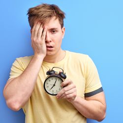 Sleep-deprived man holding alarm clock