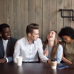 Young group of people chatting and laughing, sat in a cafe.