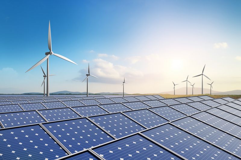 Solar farm and wind turbine with blue sky background.