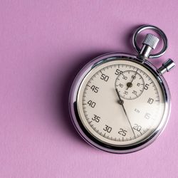 silver analog stopwatch on a lilac background