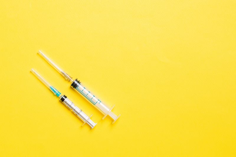 two syringes on a bright yellow background