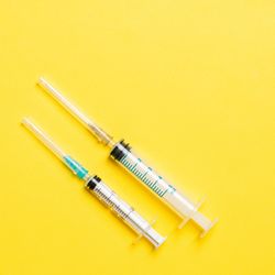 two syringes on a bright yellow background