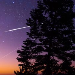 Starry Milky Way skies with comet and meteor shower, falling and shooting stars.