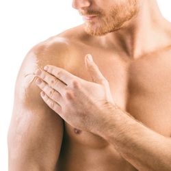 man pictured topless from waist up and eyes down rubbing clear gel onto shoulder