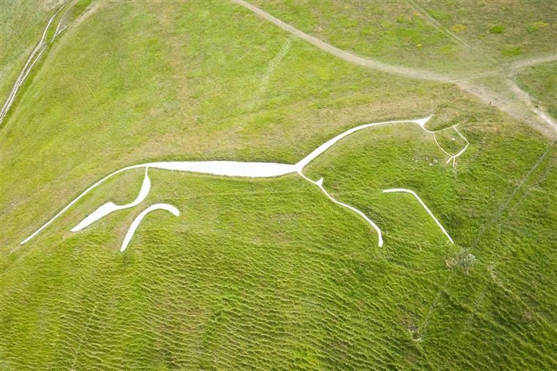 An areal photo showing the iconic Uffington White Horse carved into the green hillside. 