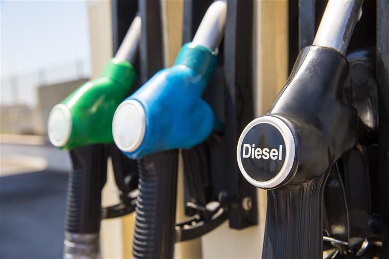 Three gas pumps, from left to right, green, blue, and one black pump labelled Diesel