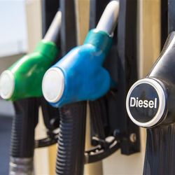 Three gas pumps, from left to right, green, blue, and one black pump labelled Diesel