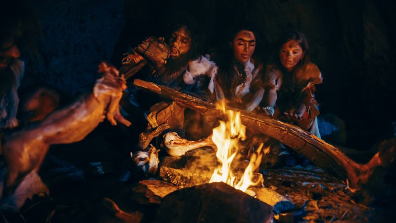 Tribe sitting in cave eating, or maybe talking.