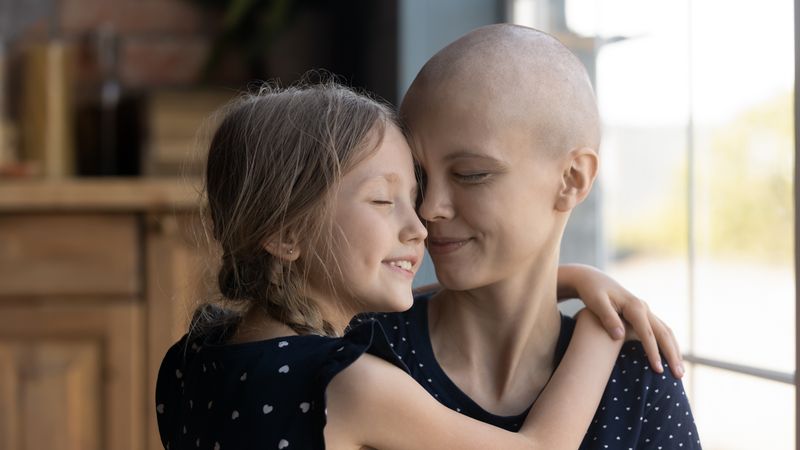 young girl smiling and embracing and older woman, who is a cancer patient