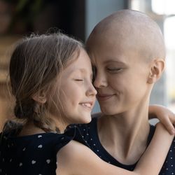 young girl smiling and embracing and older woman, who is a cancer patient