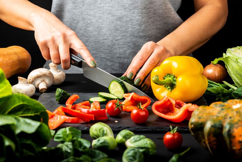 close up of someone's hands cutting vegetables with a knife