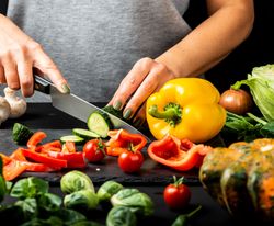 close up of someone's hands cutting vegetables with a knife