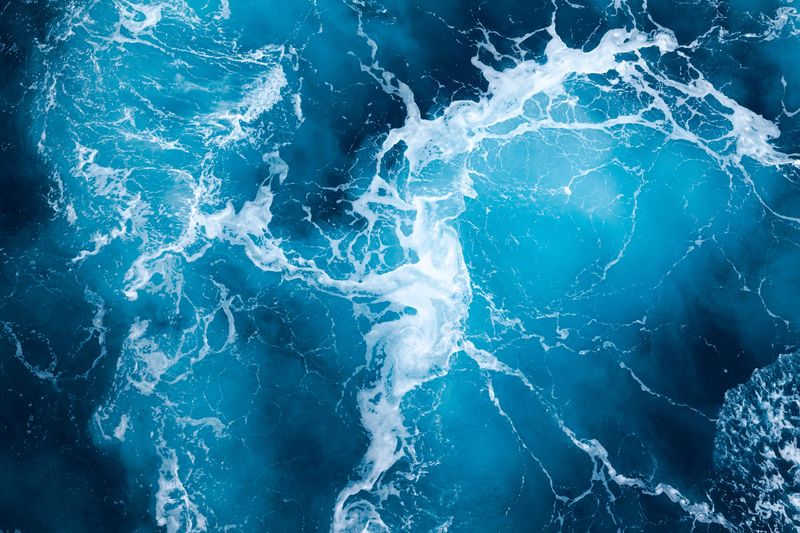 Aerial view of ocean water, wave foam