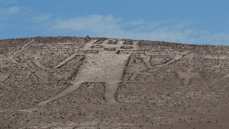 the atacama desert geoglyph etches 119 meters across a hillside, he has a spiky had and what looks like a trident