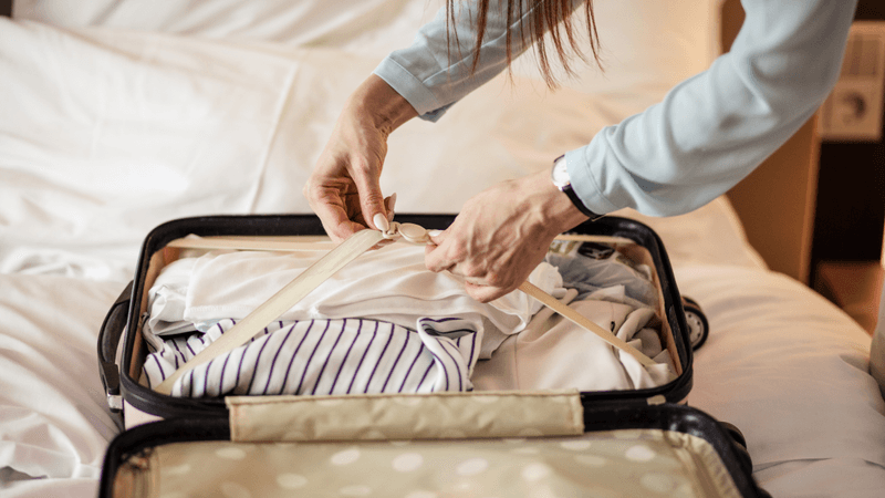 woman unpacking suitcase on bed after holiday