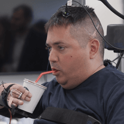 Keith Thomas lifts and drinks from a cup on his own thanks to a brain implant that is helping him to overcome paralysis caused by an injury.