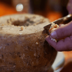 someone cutting into a wheel of casu marzu