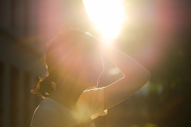 Silloute of a woman Infront of hot weather with sun flare due to climate change