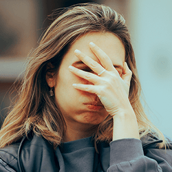 A woman with a palm to her face.