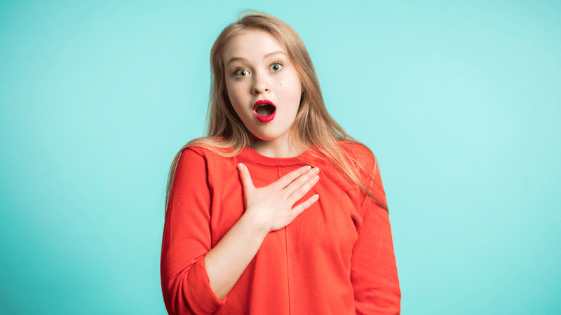 a woman shocked, someone made her jump, she is surprised and holding her chest