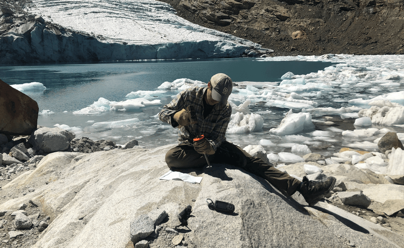 A scientist collects a sample of bedrock from the Queshque Glacier in the Peruvian Andes Mountains.  