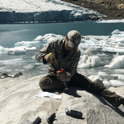 A scientist collects a sample of bedrock from the Queshque Glacier in the Peruvian Andes Mountains.  