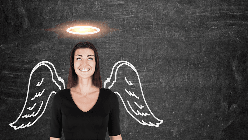 Woman standing infront of a blackboard with a halo and wings drawn on