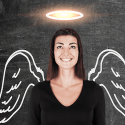 Woman standing infront of a blackboard with a halo and wings drawn on