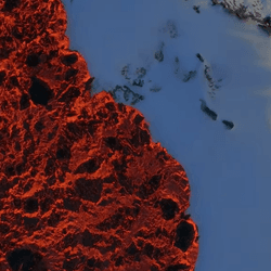 Red hot lava oozes across a snowy landscape during the eruption at Sundhnukagigar, Iceland.