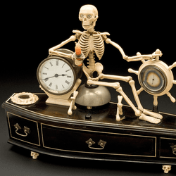 an old alarm clock of a skeleton sitting on a coffin