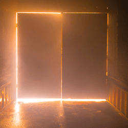 a dark corridor, the door at the end is backlit by a fire