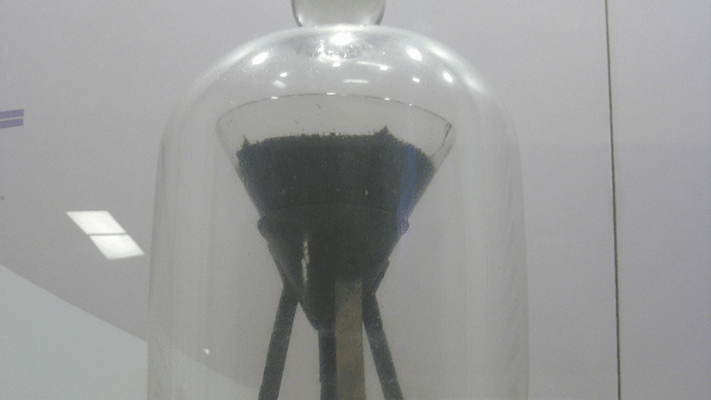 A funnel containing pitch, inside a larger display jar.