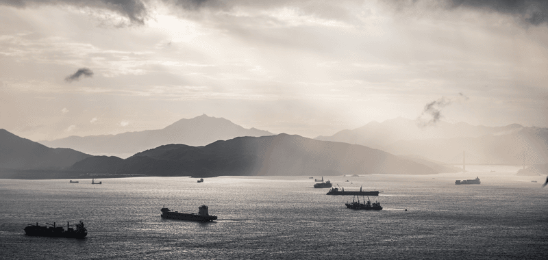 Container ships cruise through the silver-tinged sunset of the South China Sea.  Image credit: Gorma Kuma/Shutterstock.com