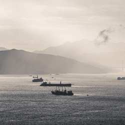 Container ships cruise through the silver-tinged sunset of the South China Sea.  Image credit: Gorma Kuma/Shutterstock.com