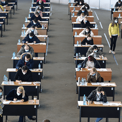 Students sitting exams in a large room.