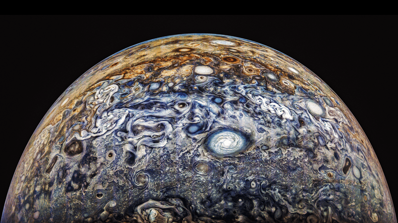 A portion of jupiter is visible and it is all swirls and vortices bit and small all around the surface